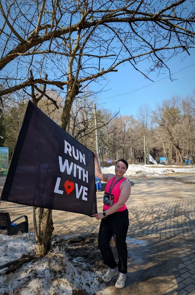Надежда у флага Run with love на заснеженной дорожке